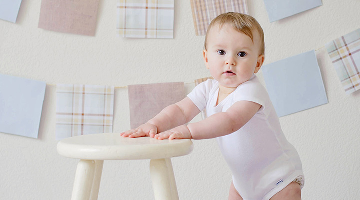 Baby steht an einem Hocker – Babygrößen auf einen Blick